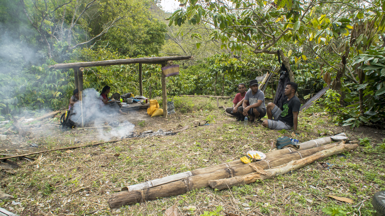 A bonfire picnic awaits in Nando’s coffee plantation at the end of the trek. Seated under the coffee tree are (from left) Eman, Igen Degu (our driver) and Nando. Photo by Andra Fembriarto