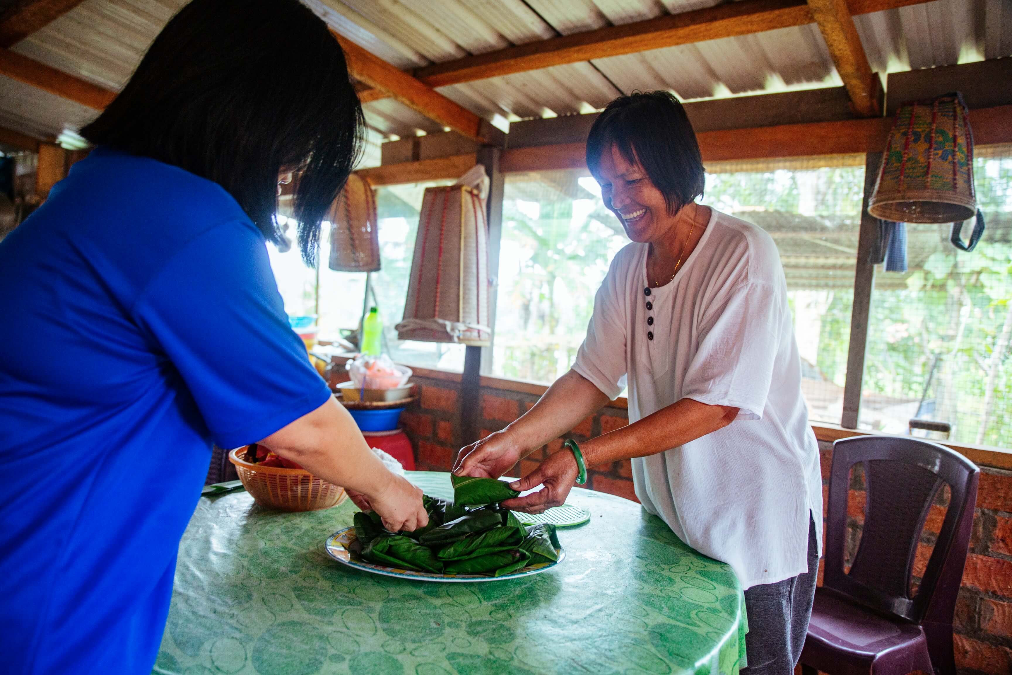 Aunty Ribed sets out a plate of food on a table. As Langit Collective's first homestay partner, and she will wow you with her deep knowledge about rice farming and agrarian life in general.