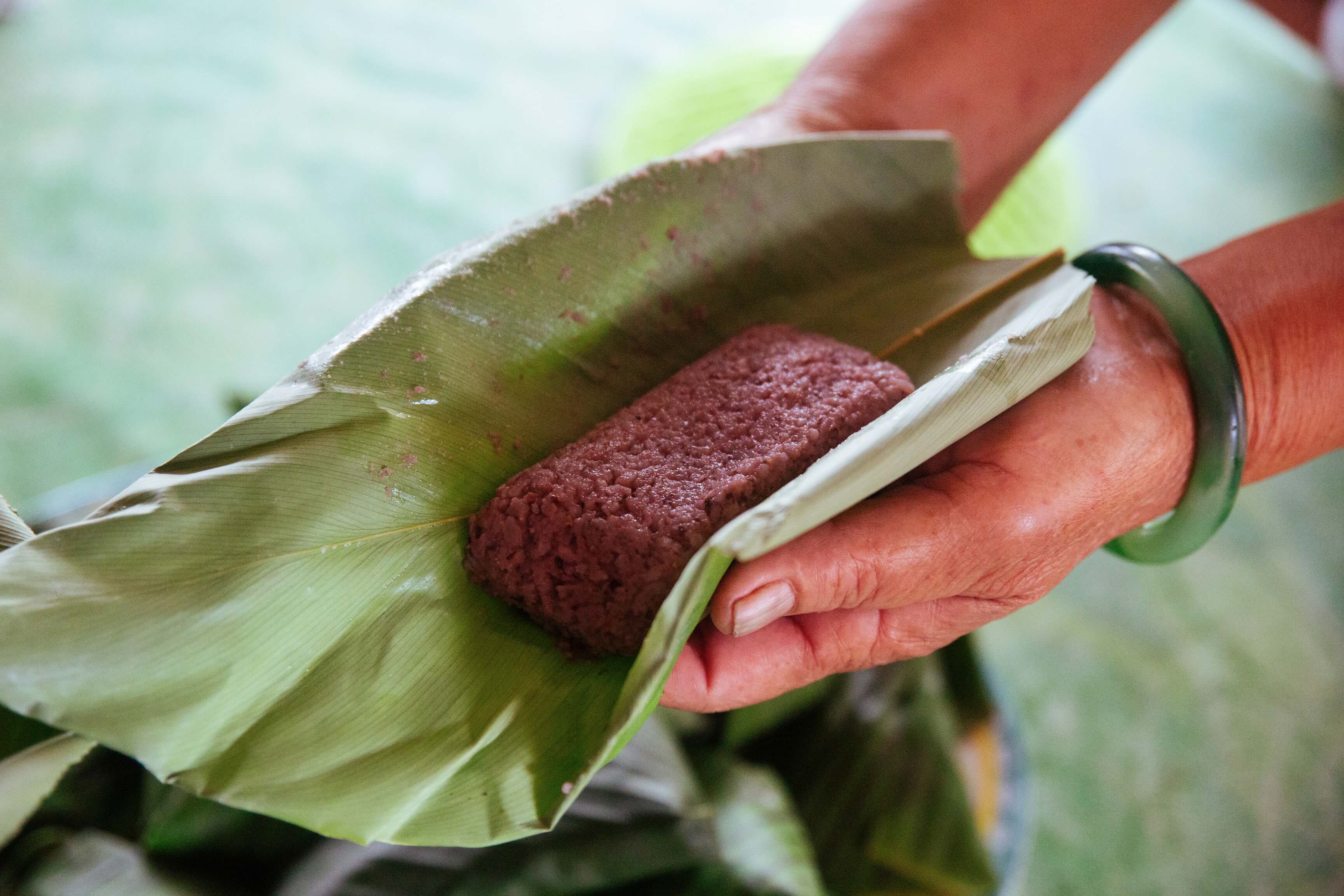Rice wrapped in banana leaf, held in the hands of Aunty Ribed. 