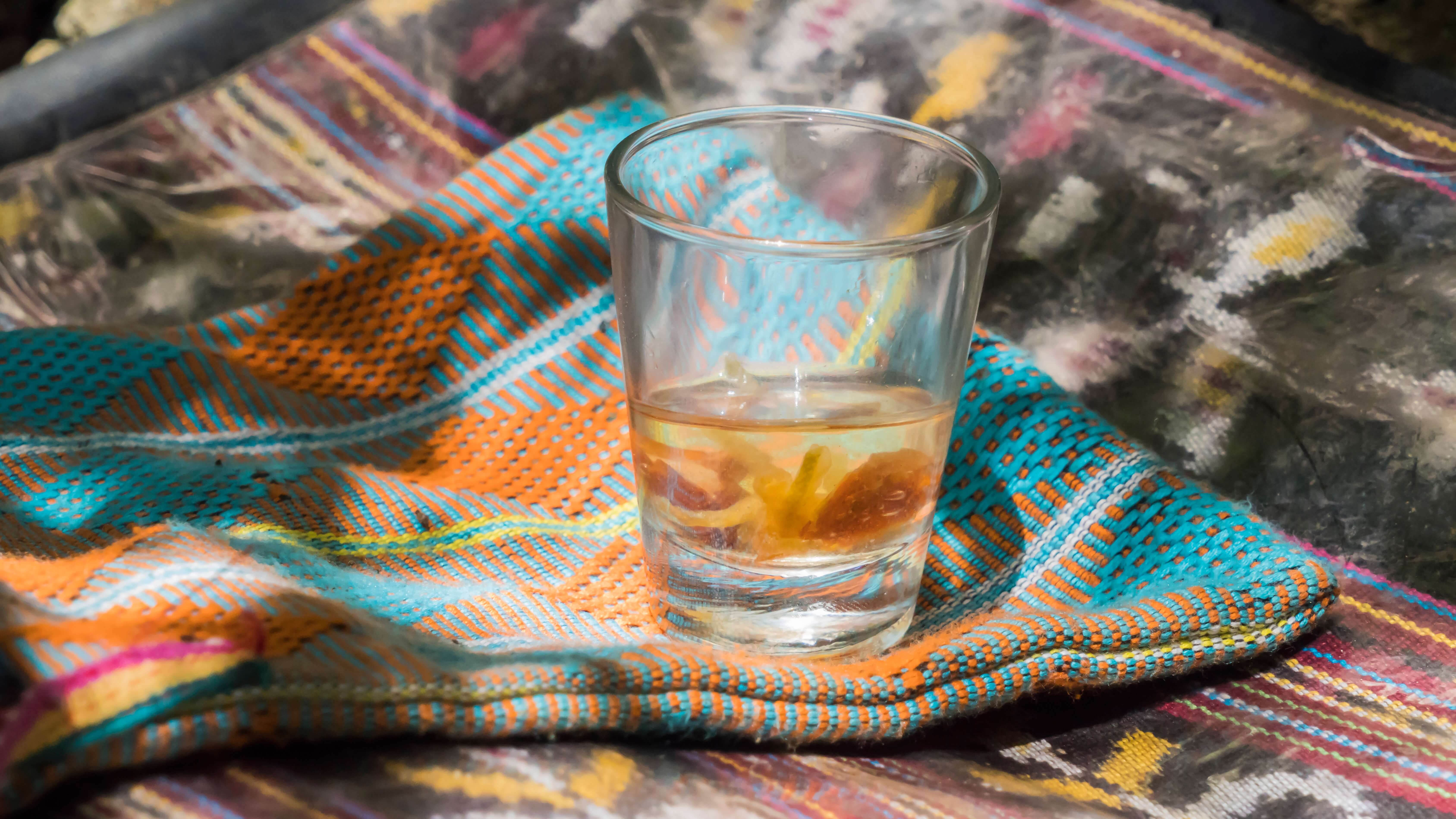 A glass of sopi lakoat, which is loquat-infused Timorese palm wine served with a garnish of dried fruit, served atop a piece of tenun lotis cloth. Photo by Andra Fembriarto
