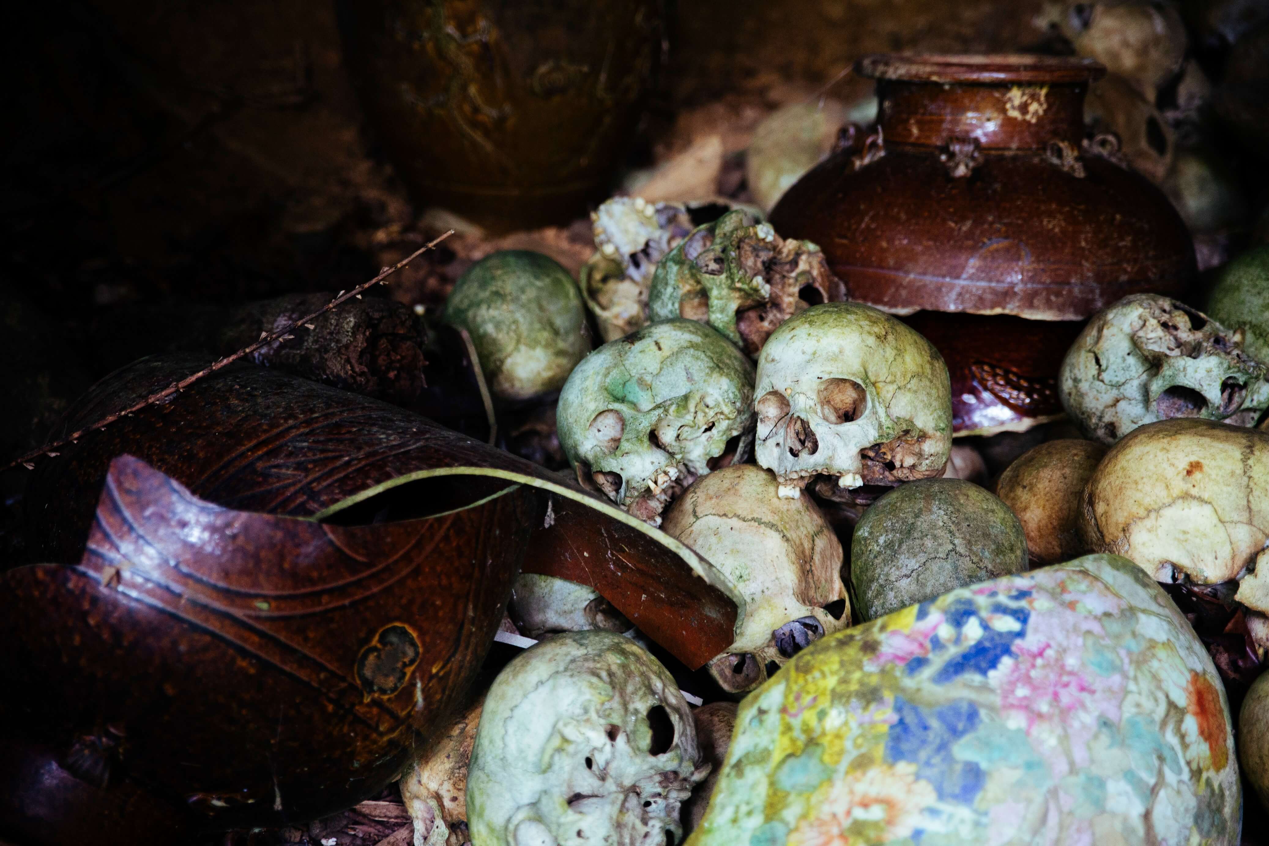 Old human skulls and ancestral jars on the forest floor, at what is possibly the only remaining Lun Bawang animistic cemetery in Long Semadoh.