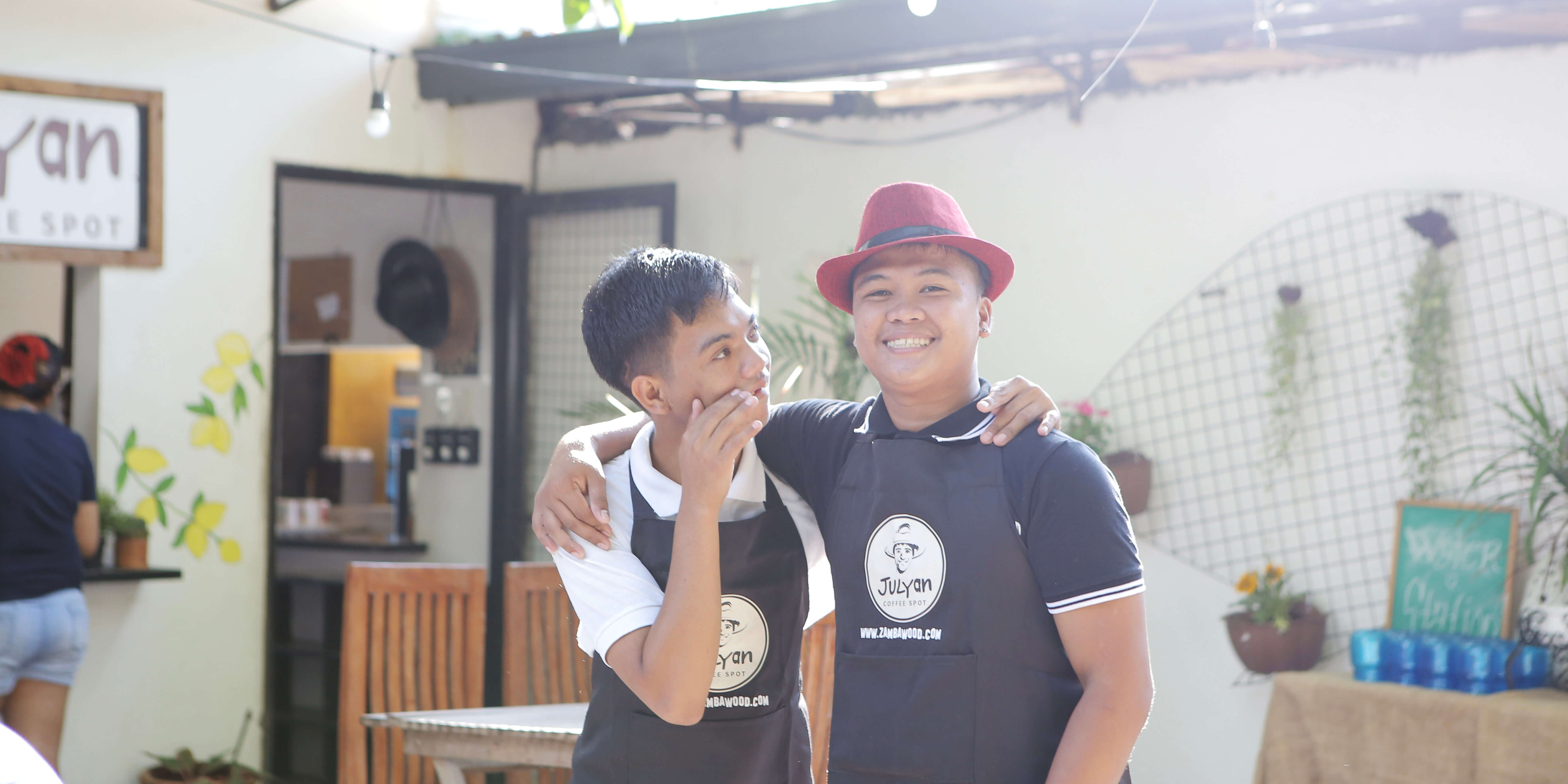 Two men standing side by side in a cafe that trains and employs people with disabilities.
