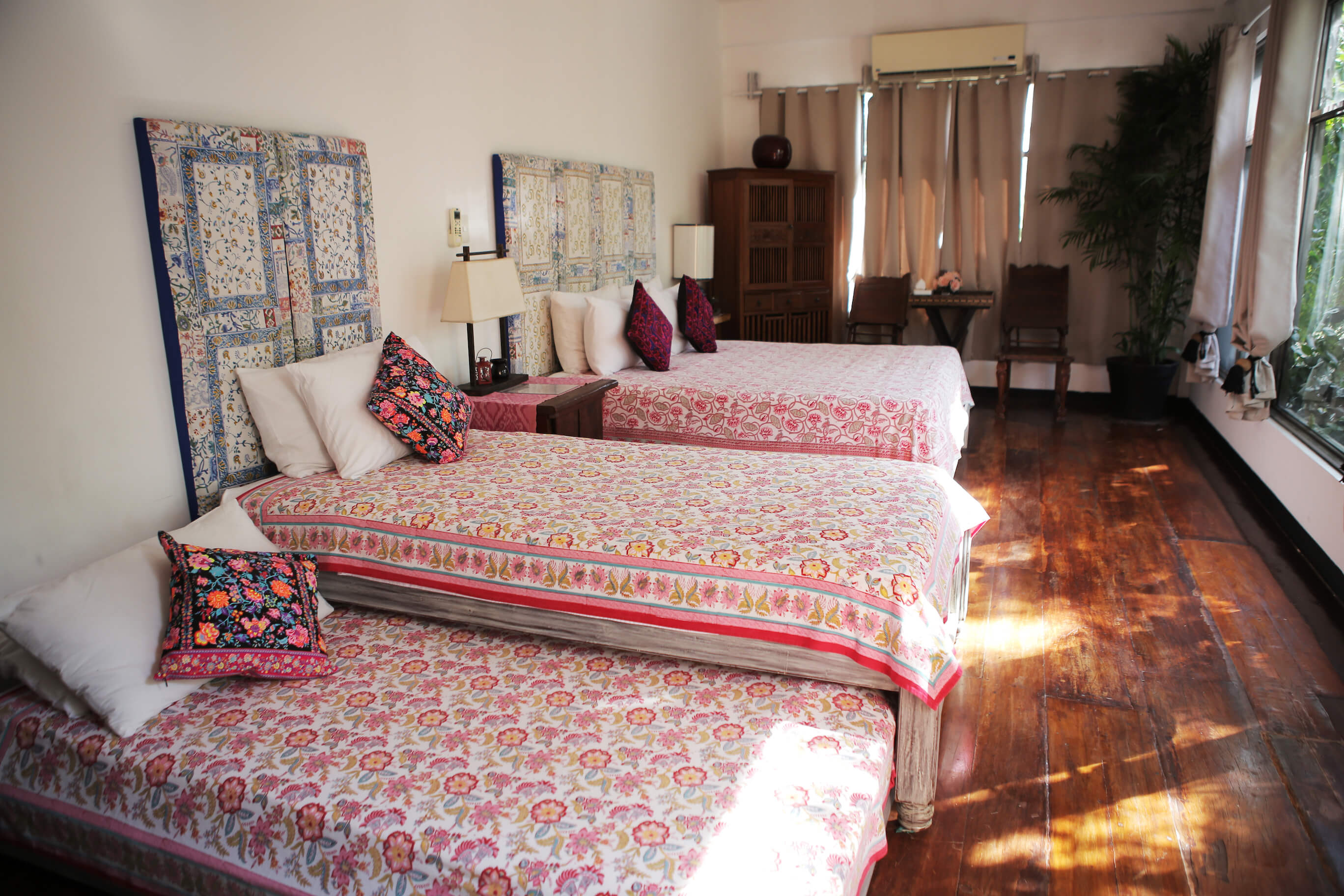 A bedroom with three twin beds made up with colourful floral bedspreads.