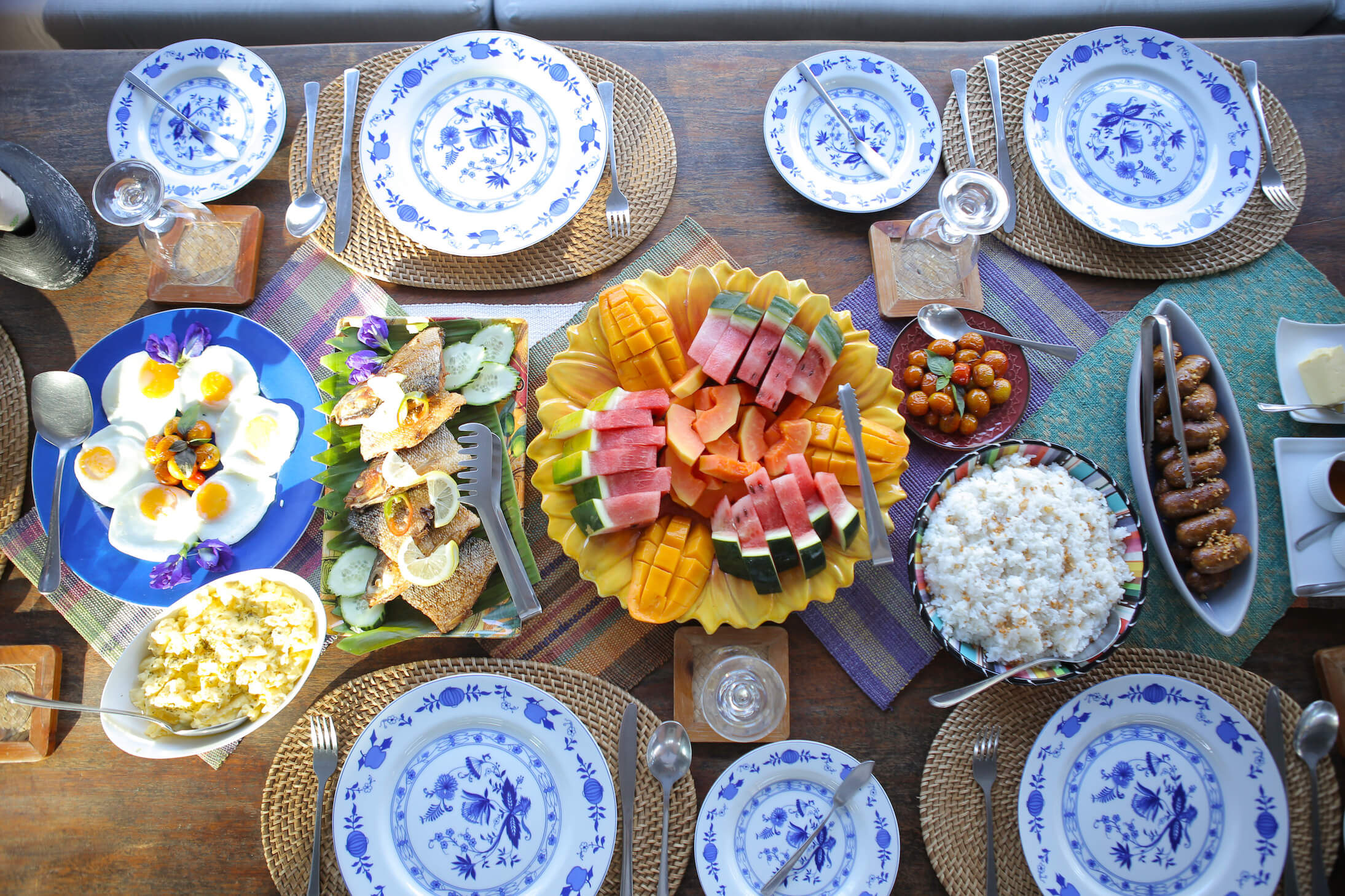 A table set with blue and white plates with food arranged in the middle.