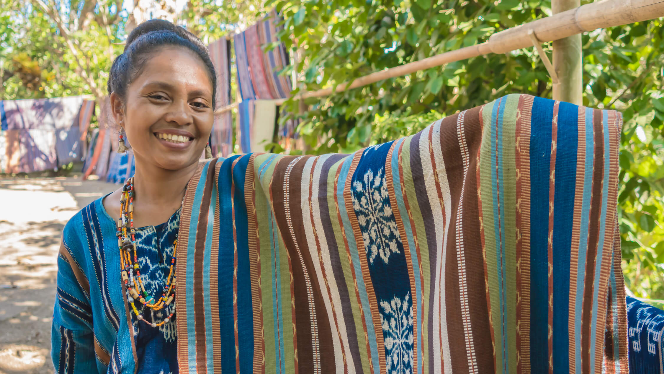  Maria Genisa and her blanket, coloured using dyes made from indigo (blue and green), turmeric and mango bark (yellow and green), morinda (brick red) and mangrove roots (chocolate brown). Photo by Andra Fembriarto