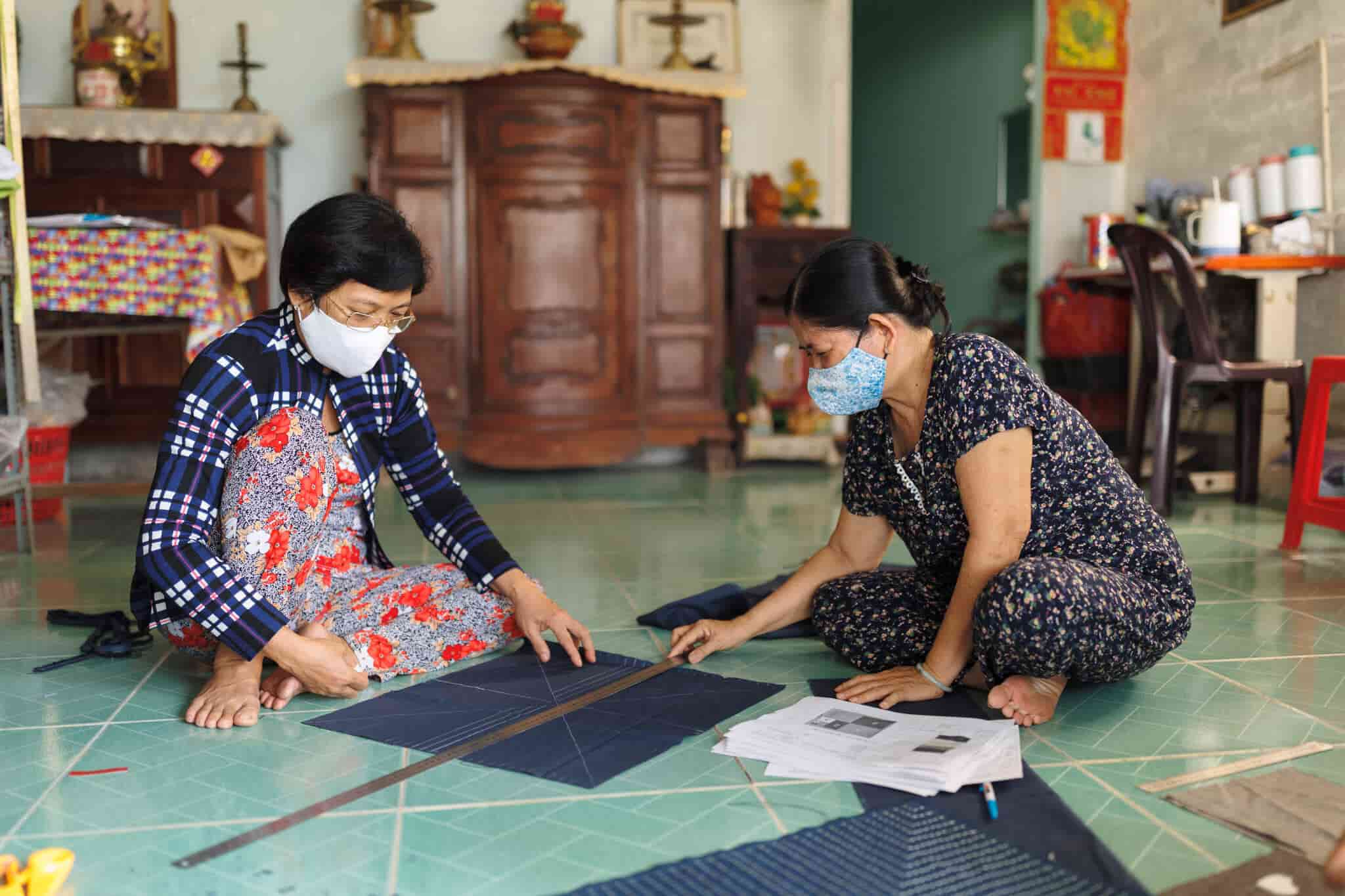 Two women measure and cut patterns for making quilts.