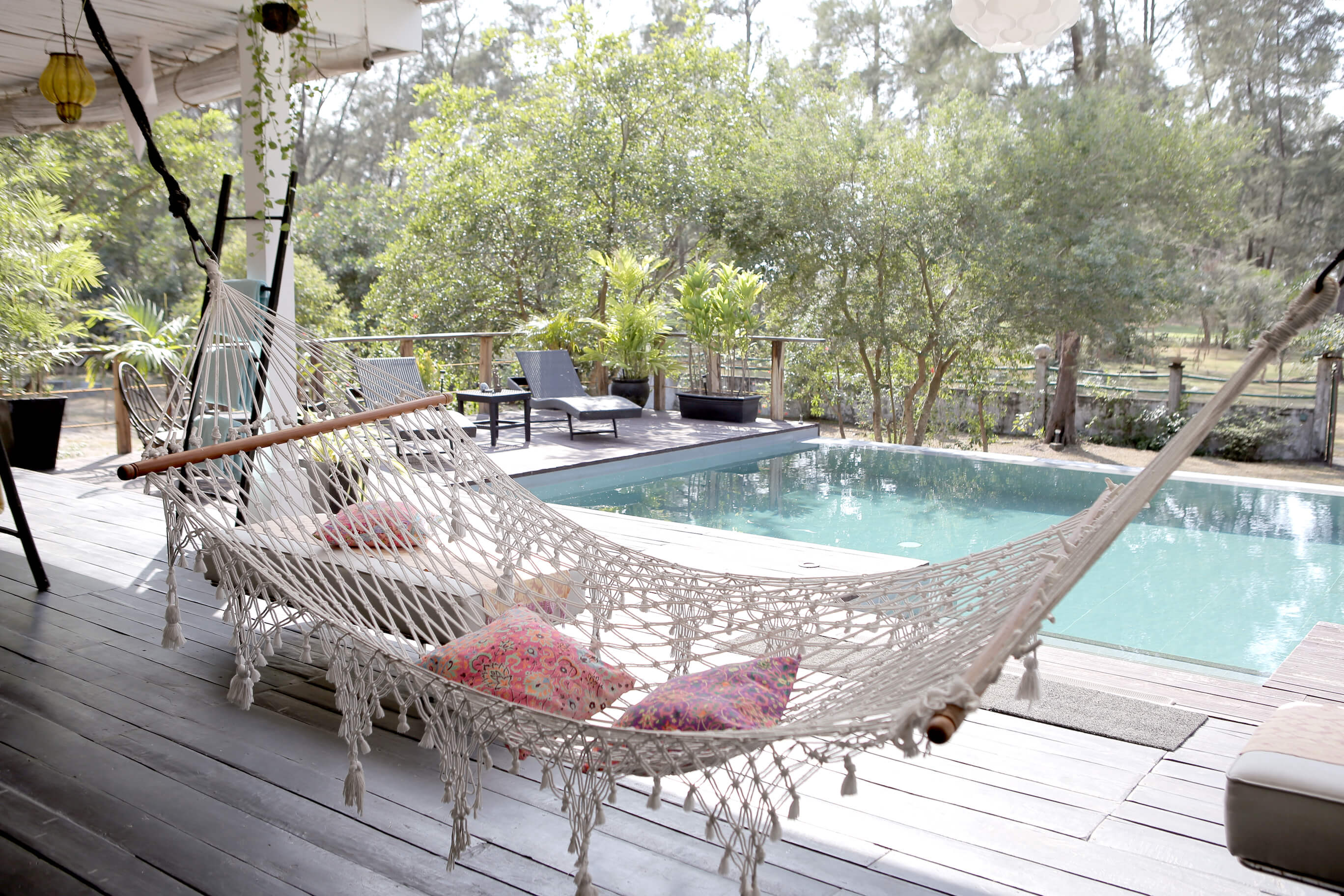 A hammock with a pool in the background. 