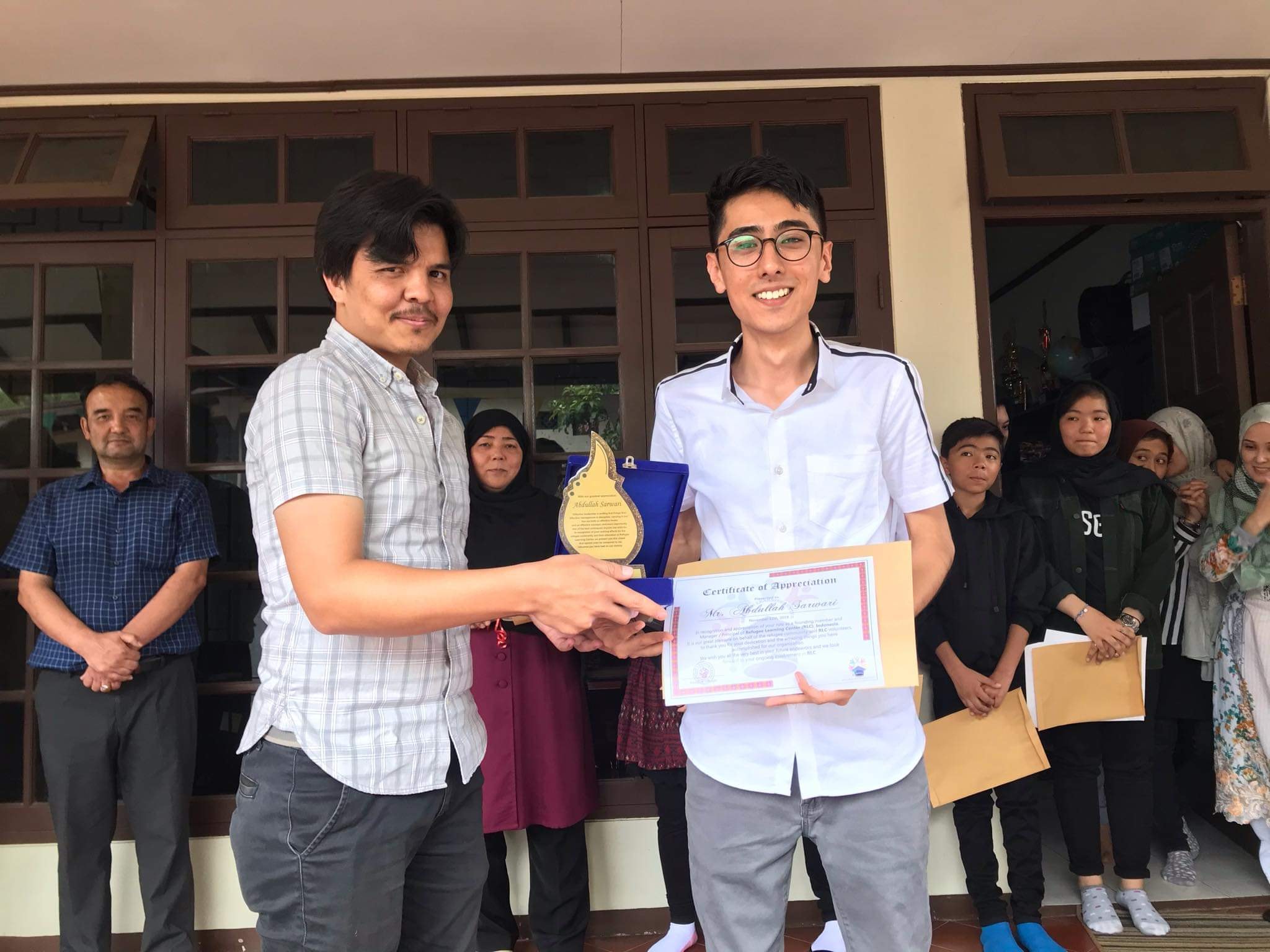 New principal Sikandar (left) presenting Abdullah (right) with a certificate of appreciation at a farewell ceremony.