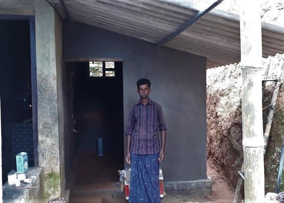 Unni Krishnan standing in front of the completed bathroom, which he hopes will be sturdy enough to withstand future disasters. Photo courtesy of SaveAGram