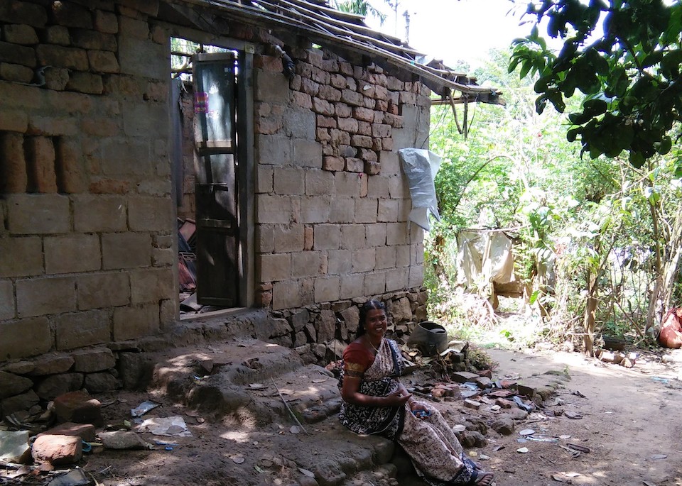 Devaki, sitting in front of her home, which was badly damaged during the flood. Photo by SaveAGram