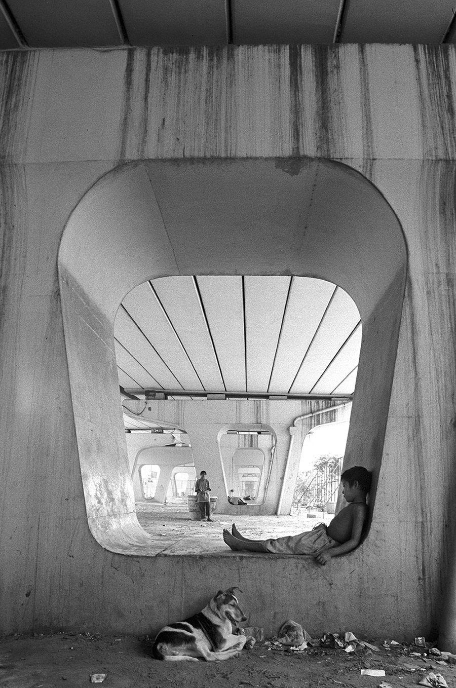 UNDER THE BRIDGE: A tired boy nestles in the niche of a concrete pillar supporting one of Delhi's busiest traffic crossings UNDER THE BRIDGE: A tired boy nestles in the niche of a concrete pillar supporting one of Delhi's busiest traffic crossings