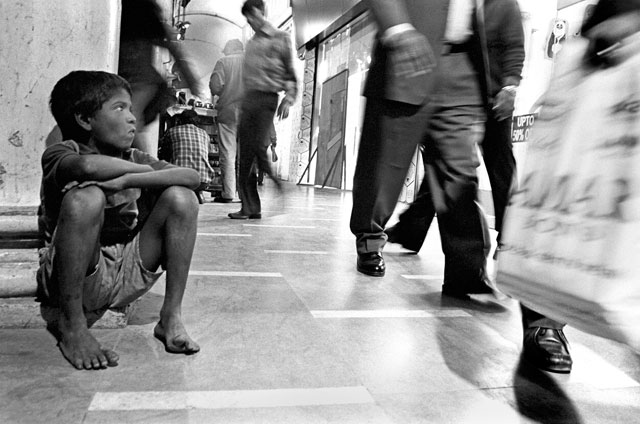 GAZING BOY: A child beggar watches the office crowd go by in downtown Delhi's Connaught Place