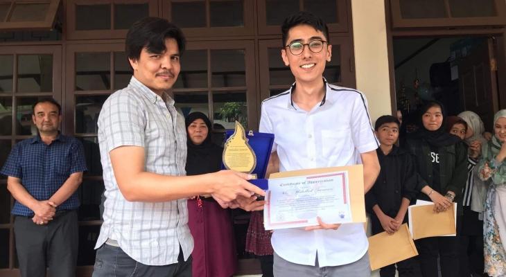 New principal Sikandar (left) presenting Abdullah (right) with a certificate of appreciation at a farewell ceremony.