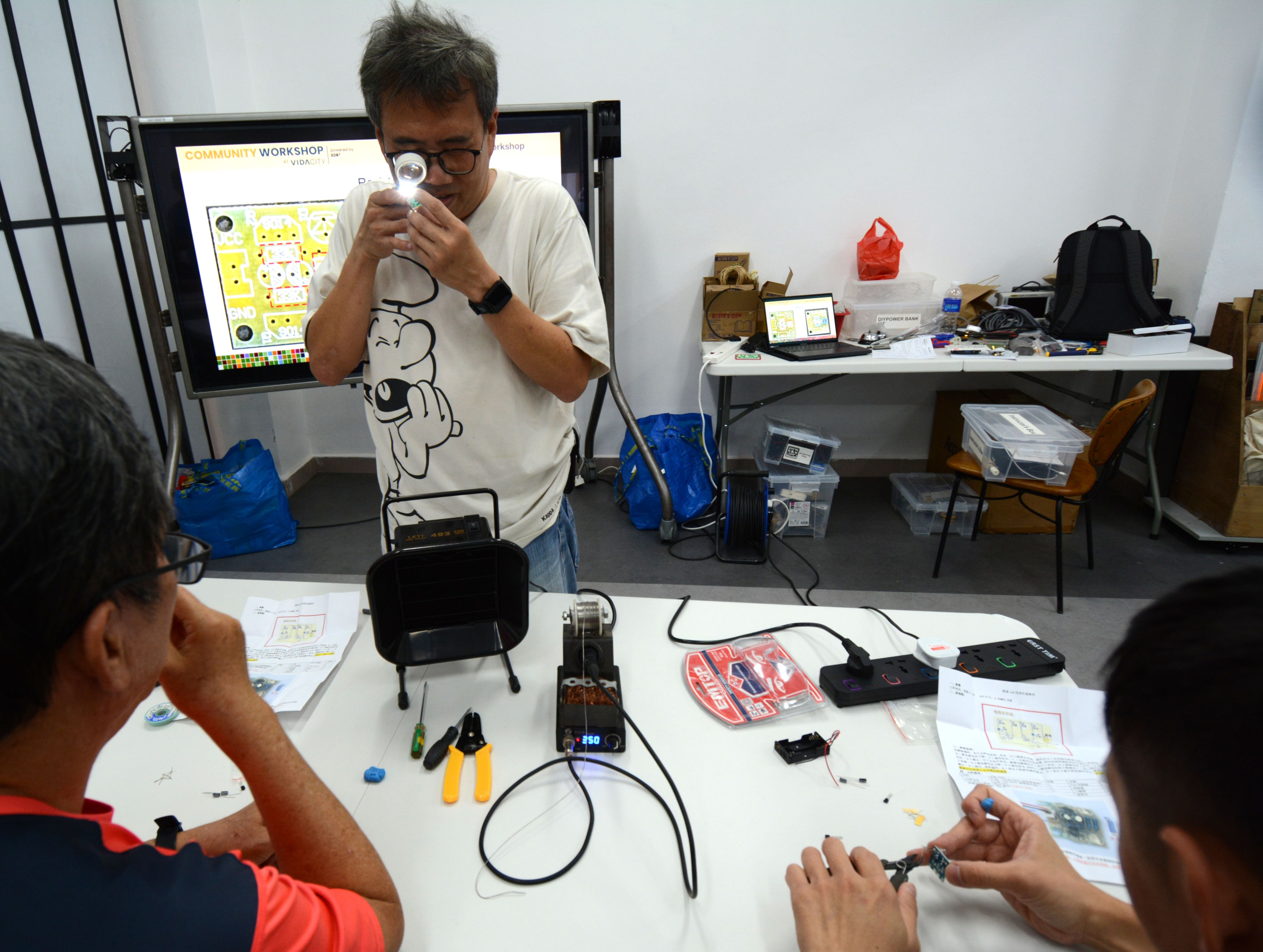 EDR2 co-founder Danny Lim inspects participants' soldering work at a workshop held at Vidacity.